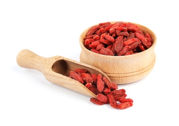 Wooden bowl and scoop of tasty dried goji berries on white background