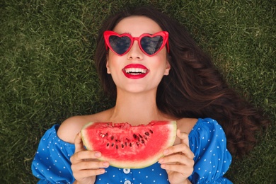 Beautiful young woman with watermelon on green grass outdoors, top view