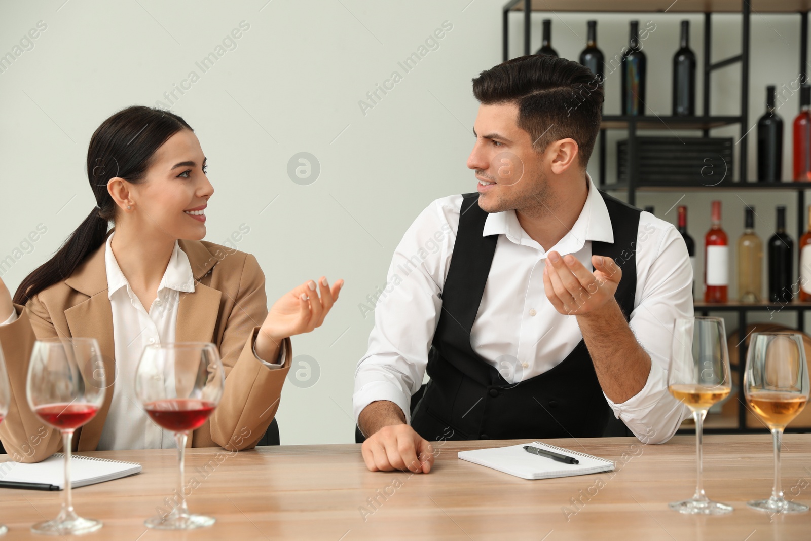 Photo of Sommeliers tasting different sorts of wine at table indoors