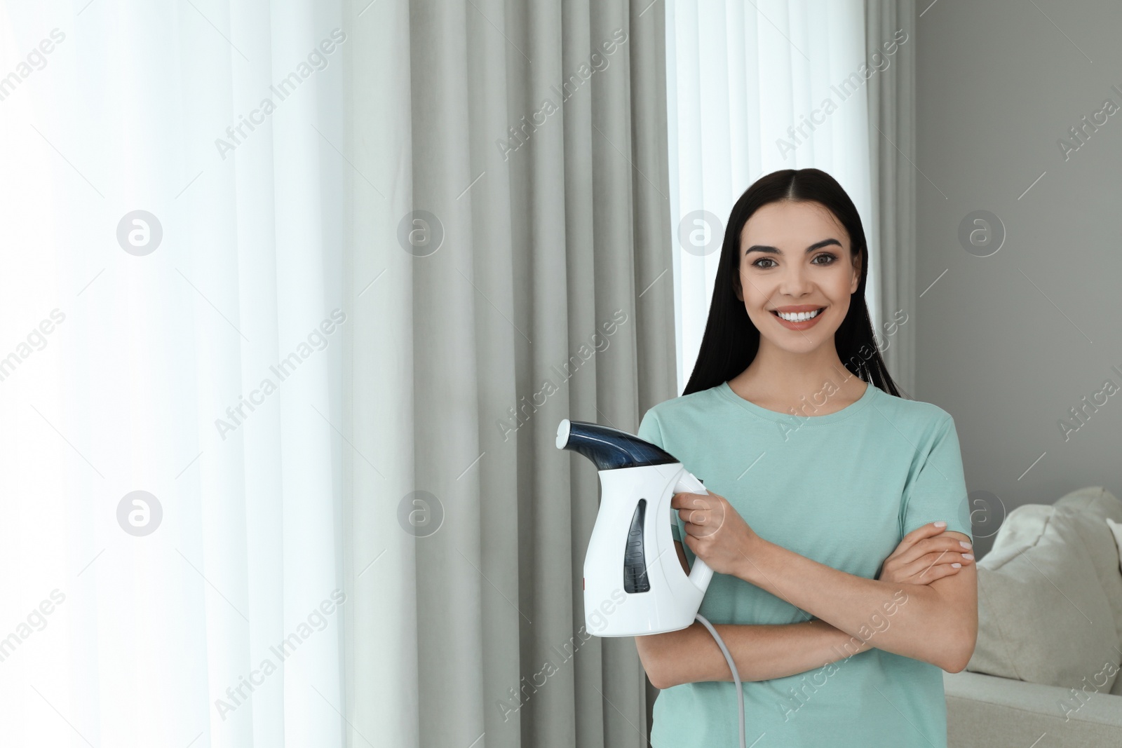 Photo of Happy woman with steam iron at home. Space for text