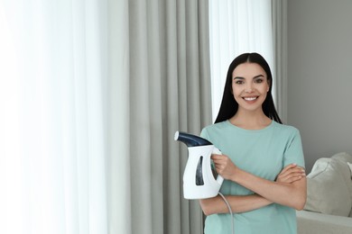 Happy woman with steam iron at home. Space for text