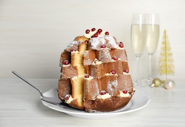 Photo of Delicious Pandoro Christmas tree cake with powdered sugar and berries on white wooden table