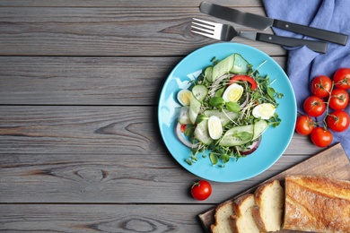 Salad with fresh organic microgreen in plate on wooden table, flat lay. Space for text