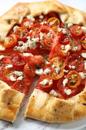 Photo of Tasty galette with tomato, thyme and cheese (Caprese galette) on table, closeup