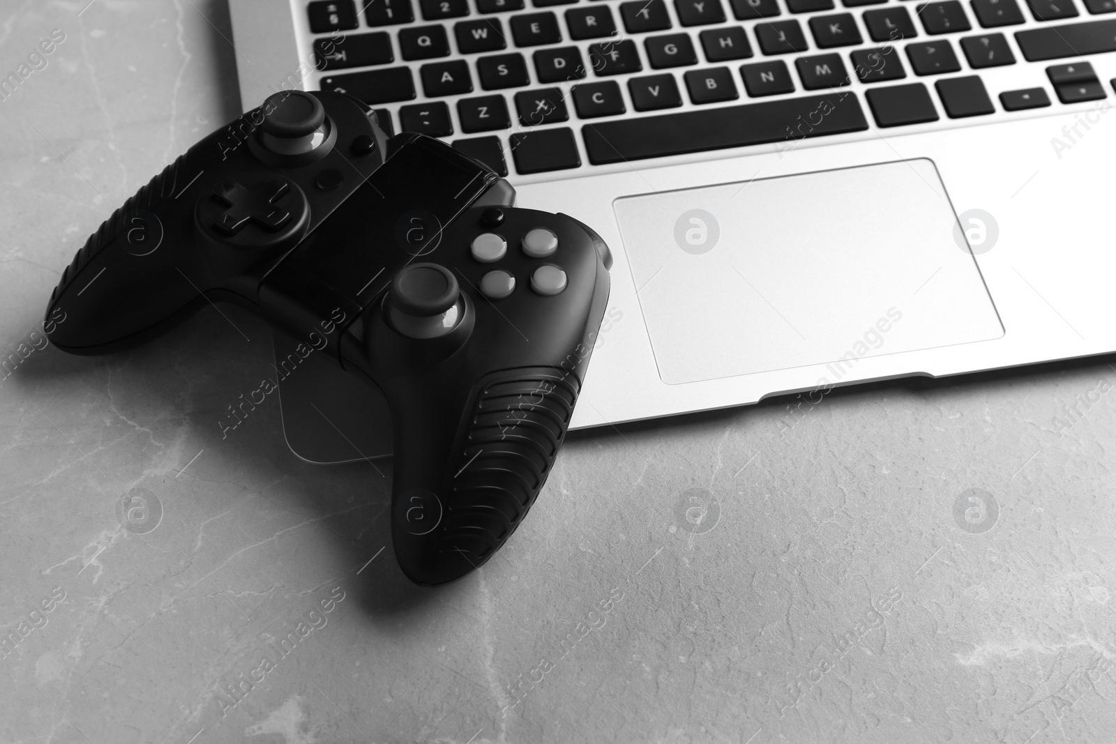 Photo of Video game controller and laptop on grey table