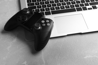 Photo of Video game controller and laptop on grey table