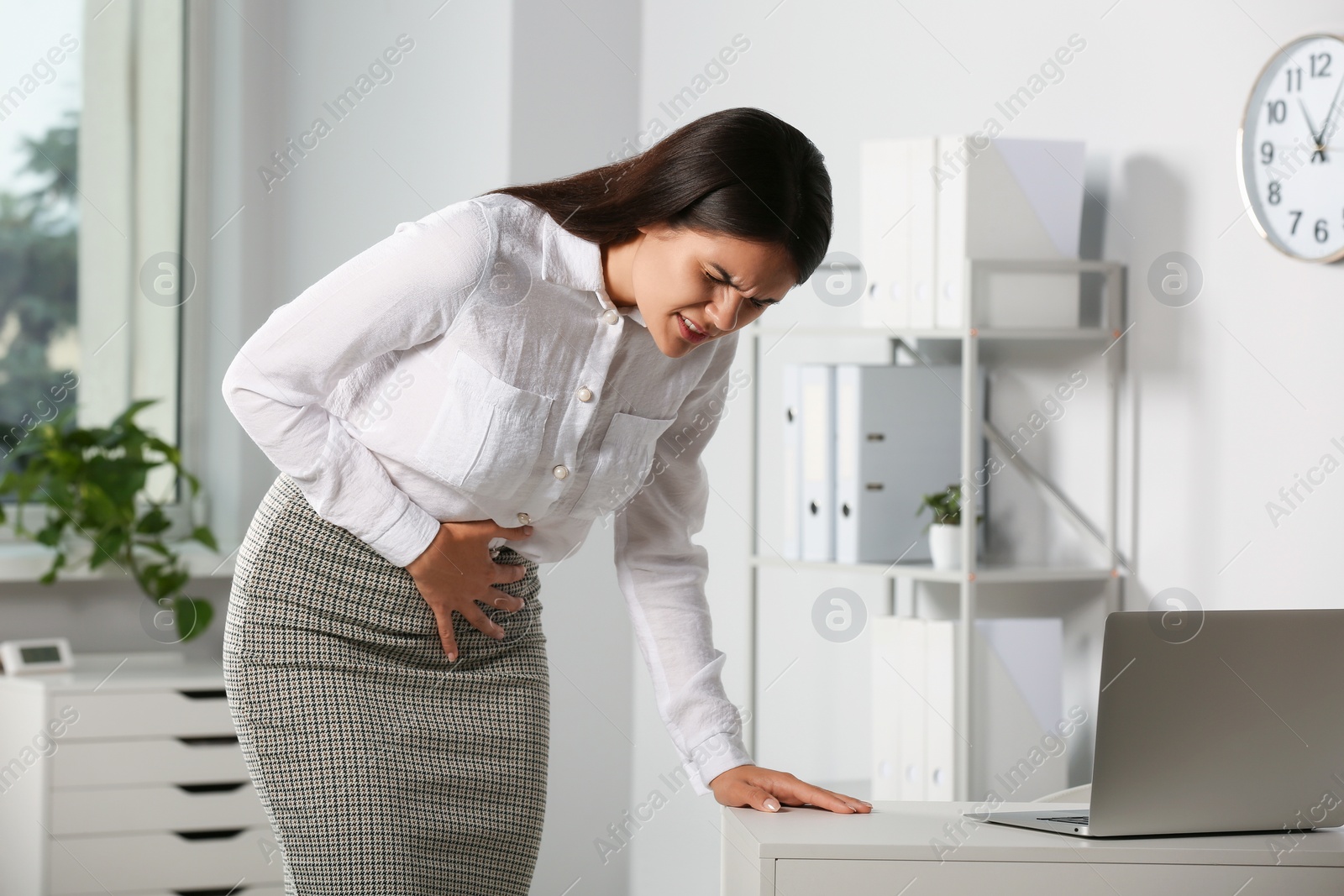 Photo of Young woman suffering from menstrual pain in office