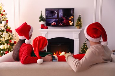 Image of Family watching festive movie on TV in room decorated for Christmas, back view