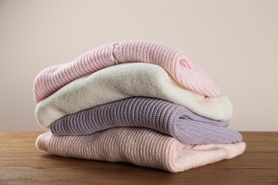 Photo of Stack of knitted sweaters on wooden table