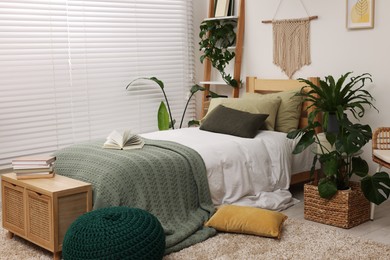 Large comfortable bed and potted houseplants in stylish bedroom. Interior design