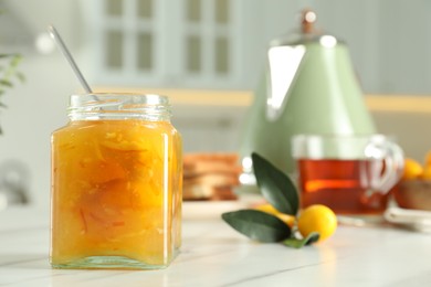 Delicious kumquat jam in jar on white marble table