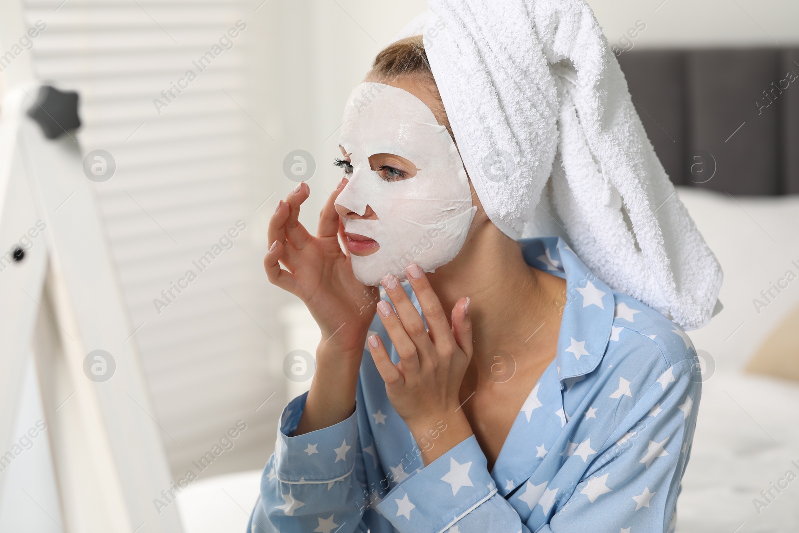 Photo of Young woman with face mask looking into mirror at home. Spa treatments