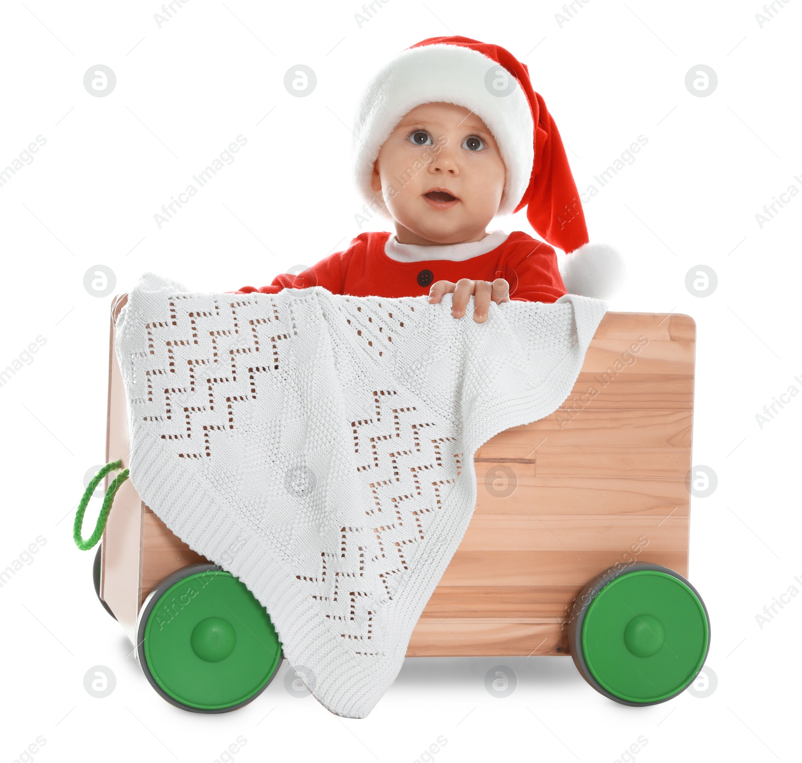 Photo of Cute little baby wearing Santa hat in wooden cart on white background. First Christmas