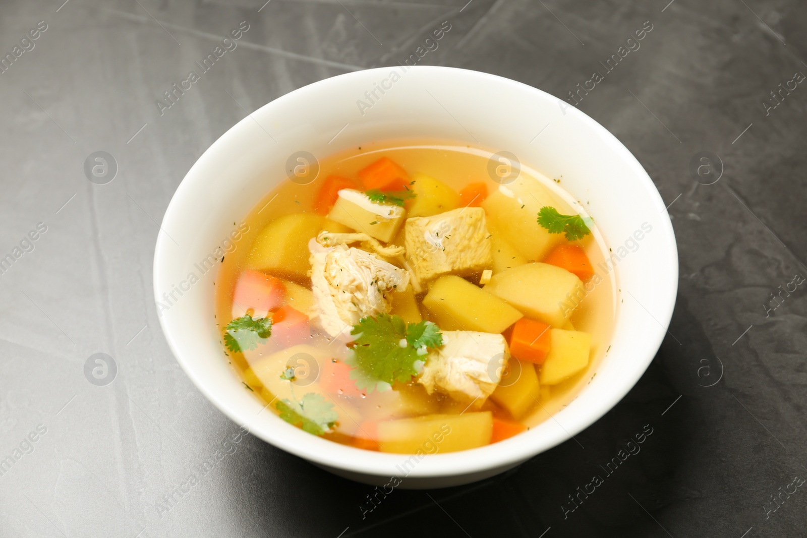 Photo of Dish with fresh homemade chicken soup on grey background