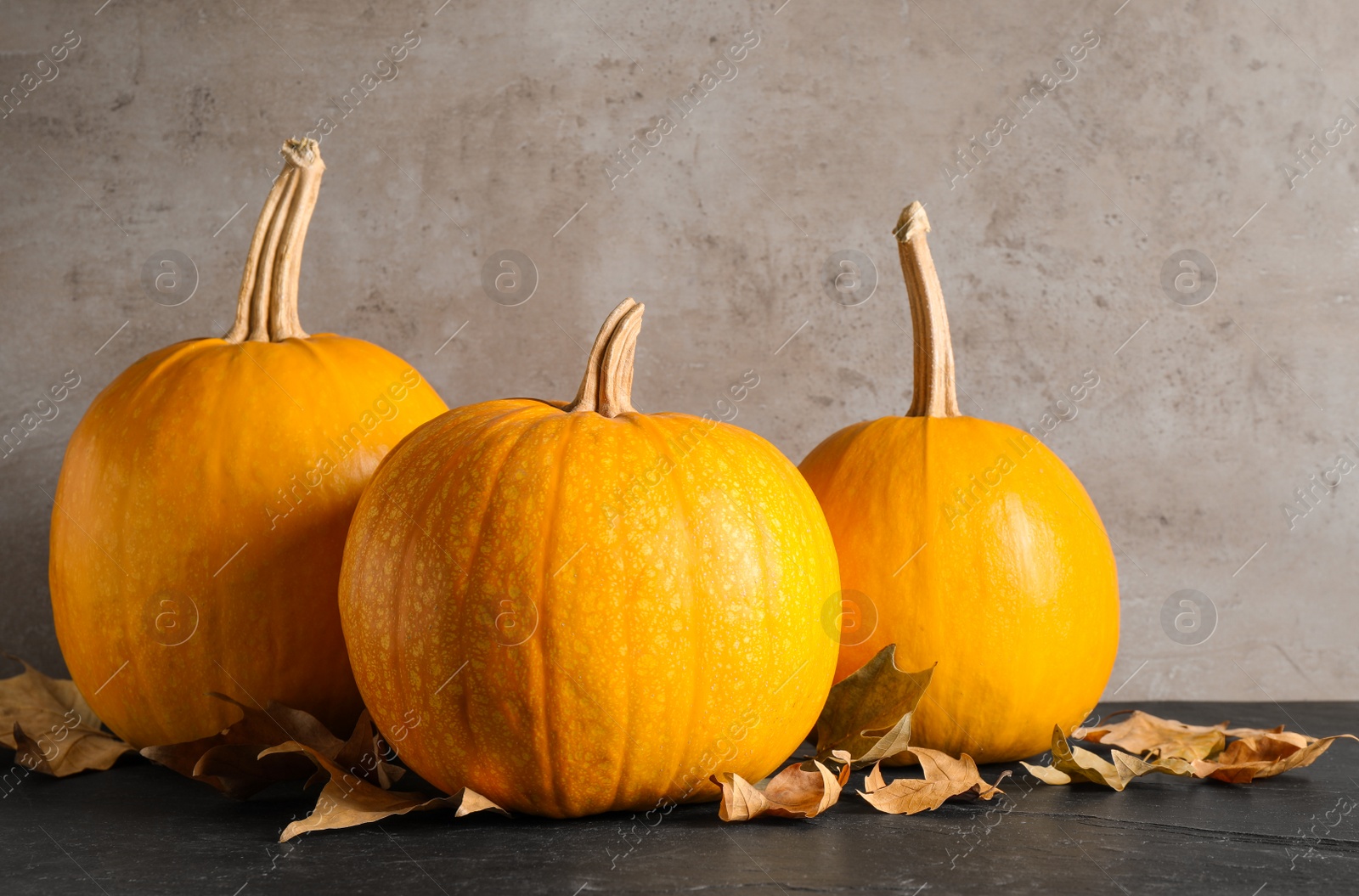 Photo of Ripe pumpkins and autumn leaves on black table