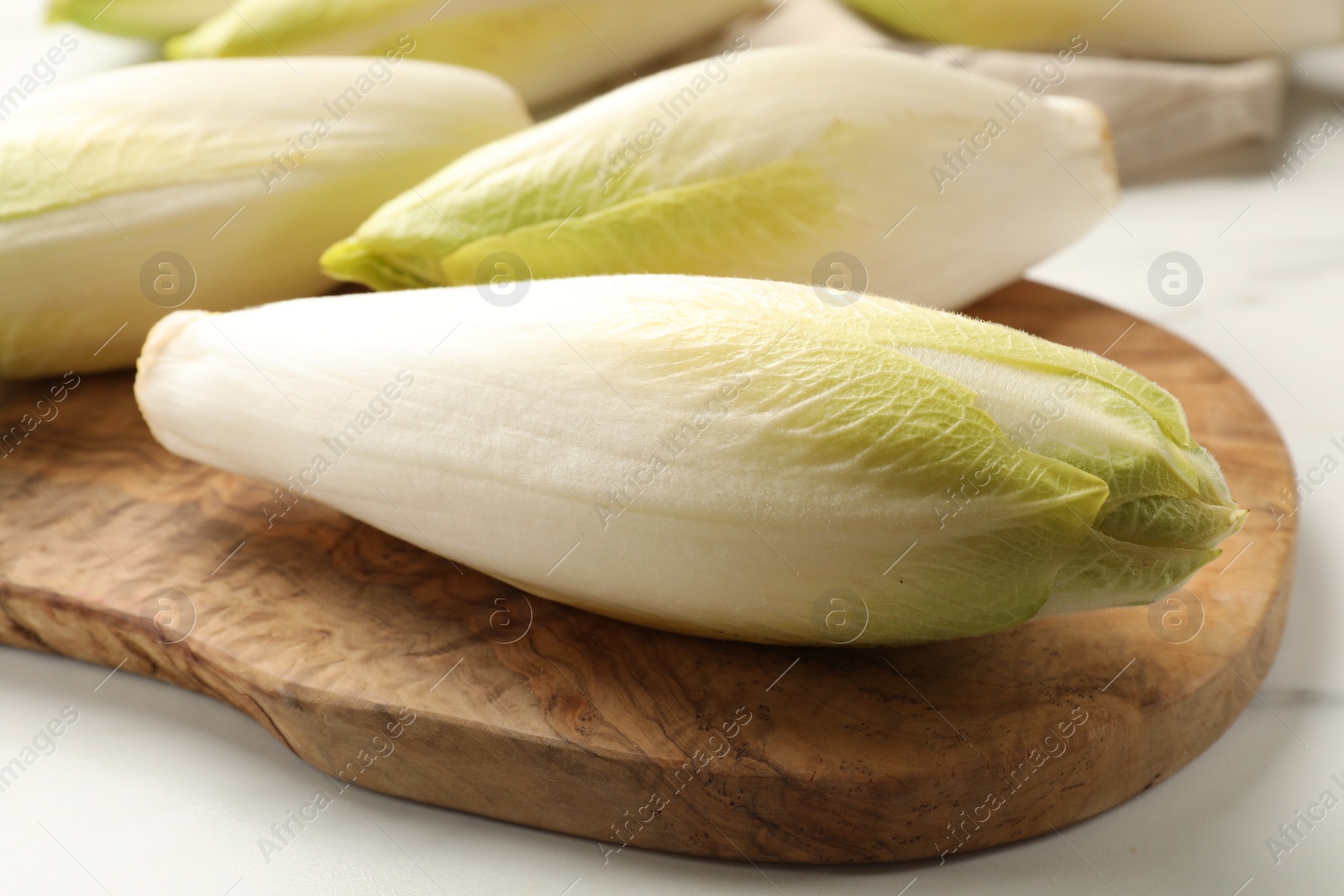 Photo of Raw ripe chicories on white marble table, closeup