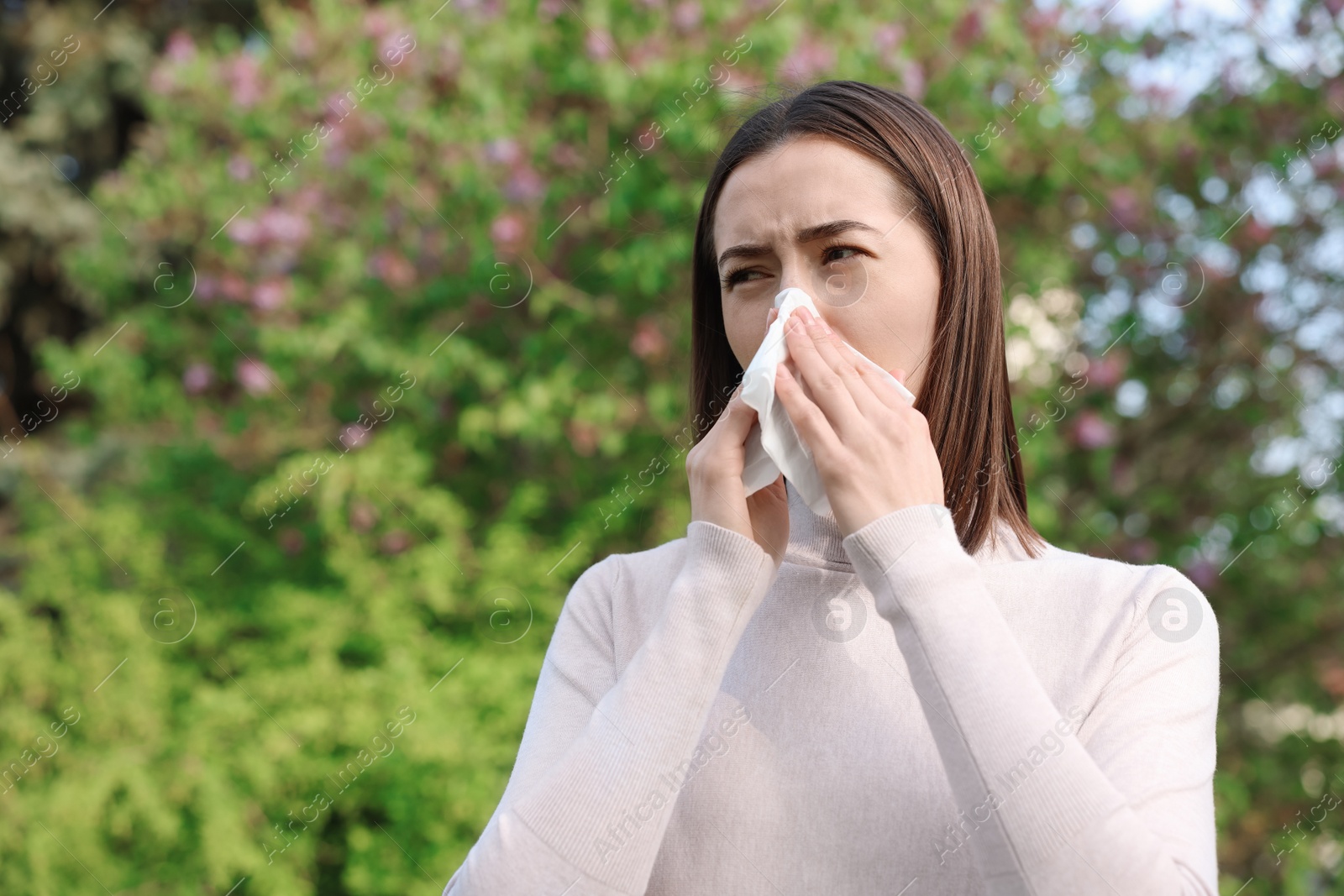 Photo of Woman with napkin suffering from seasonal allergy outdoors