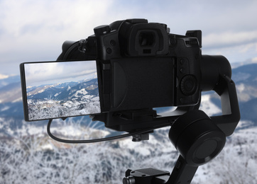 Image of Recording beautiful view of snowy mountains on professional video camera