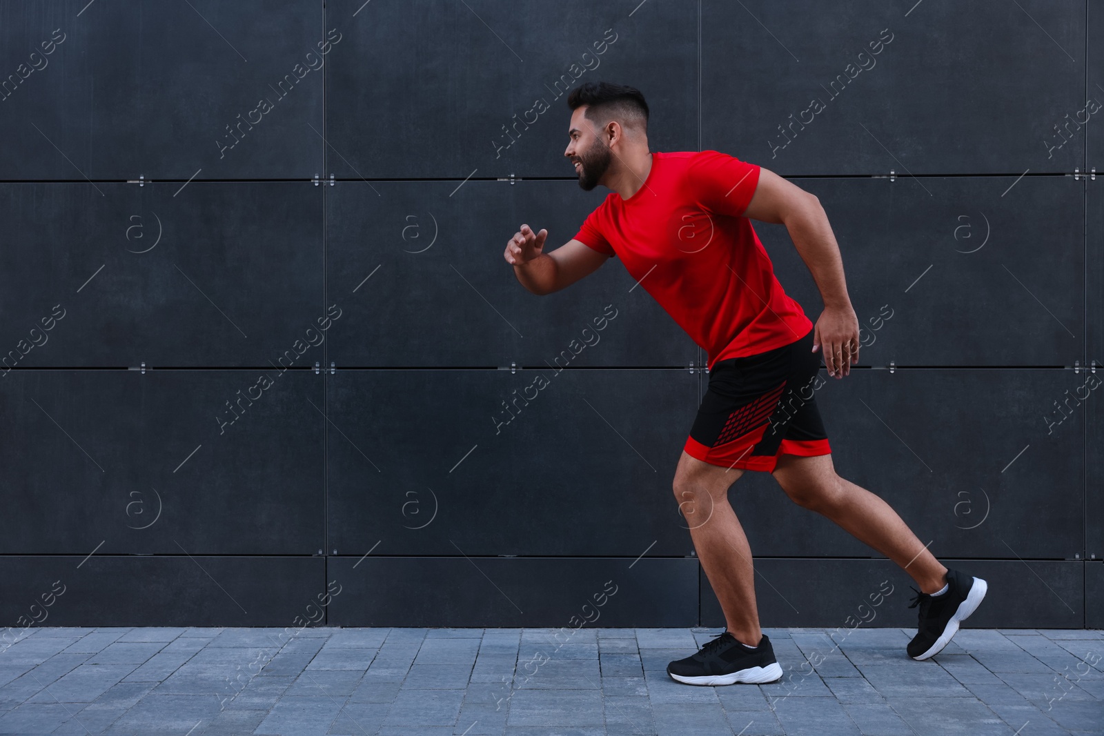 Photo of Happy man running near building outdoors. Space for text