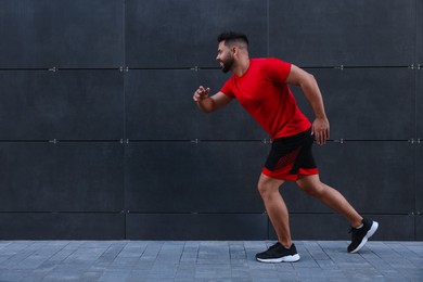 Photo of Happy man running near building outdoors. Space for text