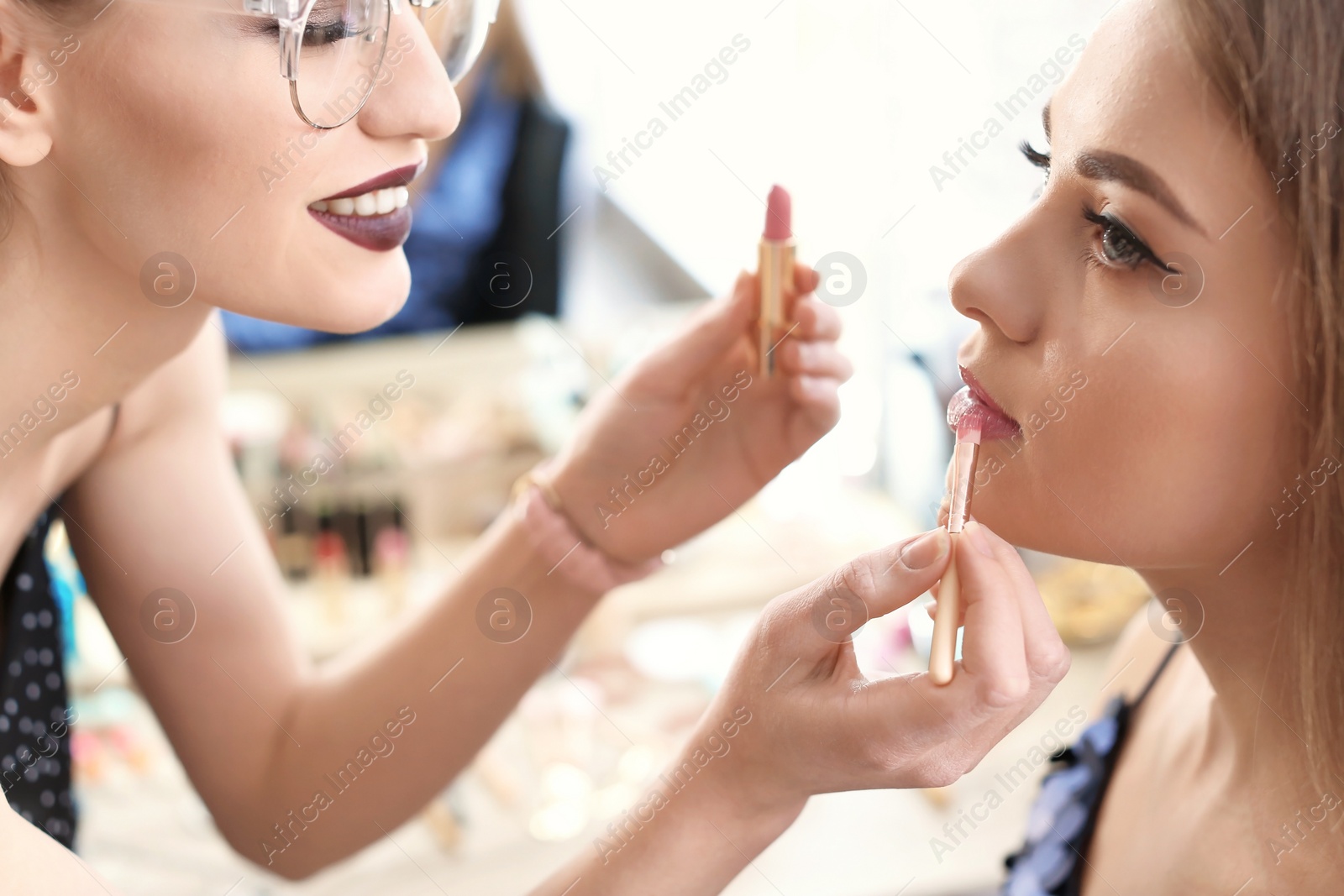 Photo of Professional makeup artist working with beautiful young woman in studio