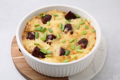 Photo of Tasty sausage casserole with green onions in baking dish on white table, closeup