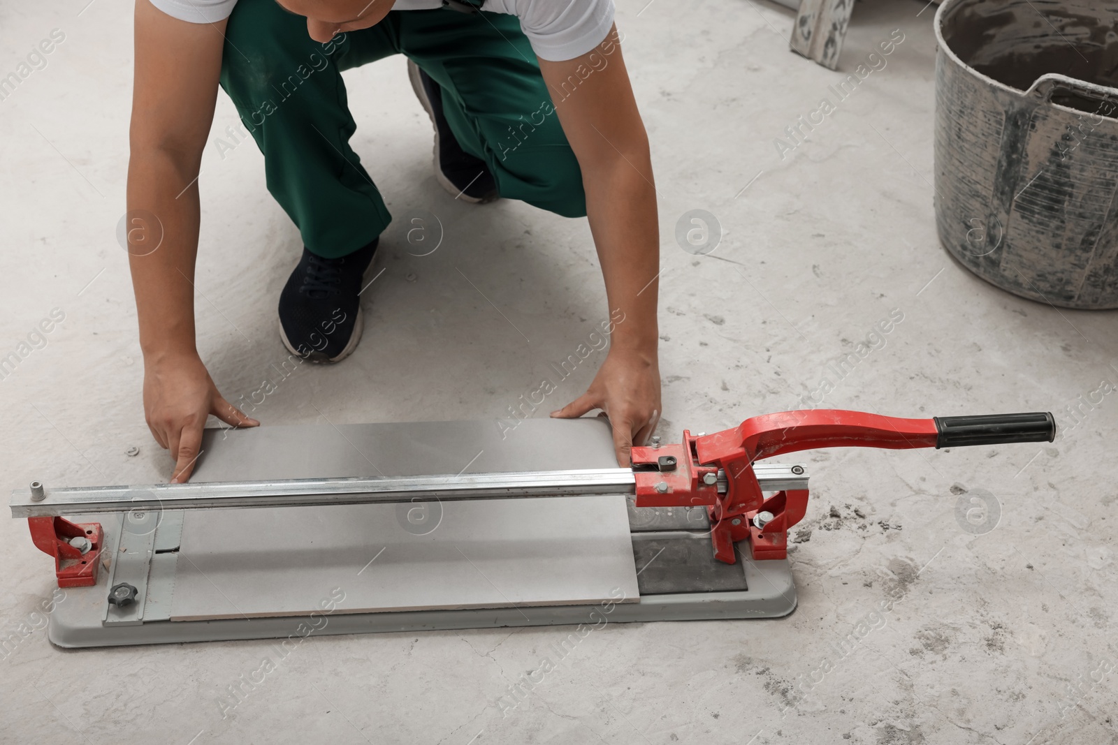 Photo of Worker using manual tile cutter on floor, closeup