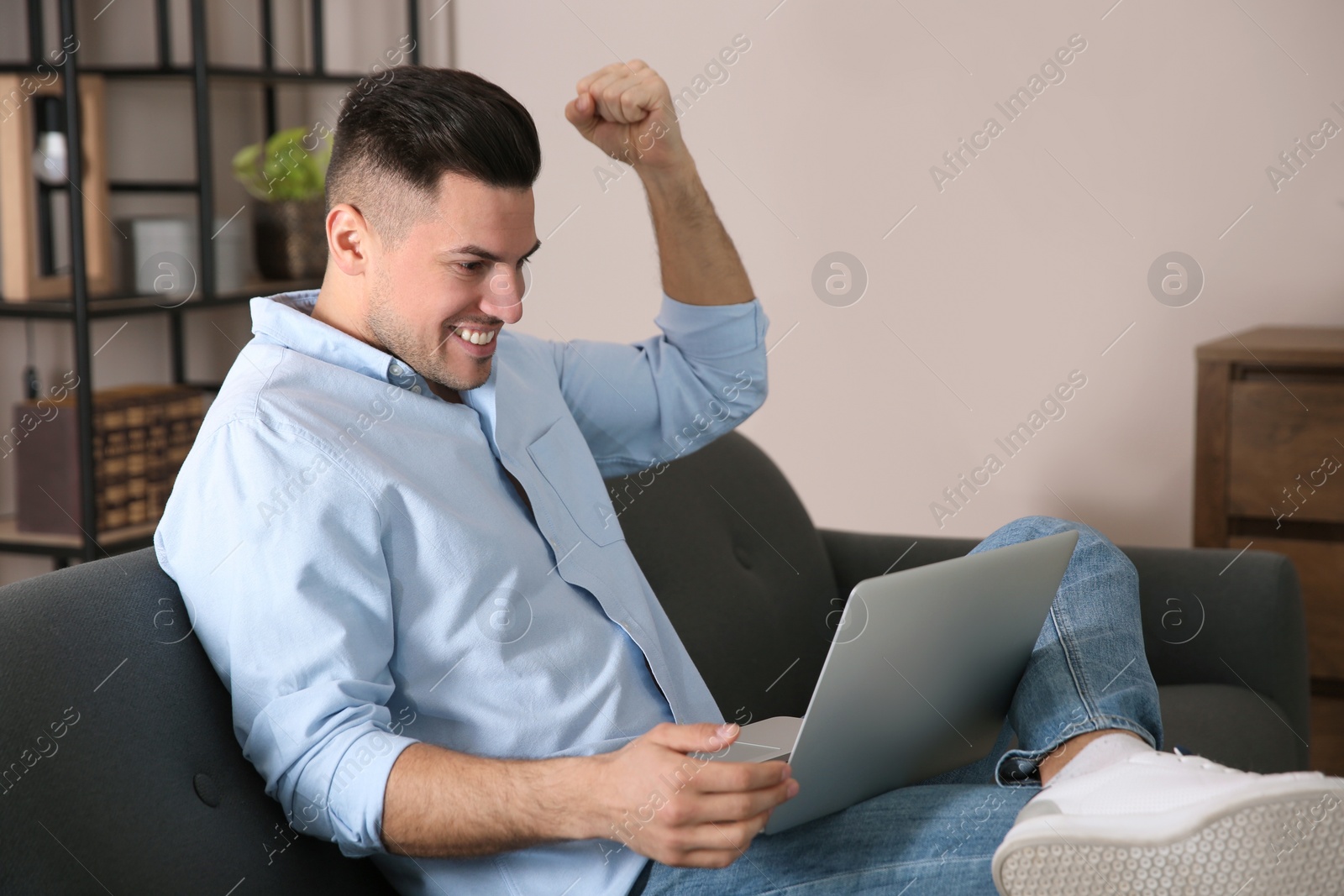 Photo of Emotional man participating in online auction using laptop at home