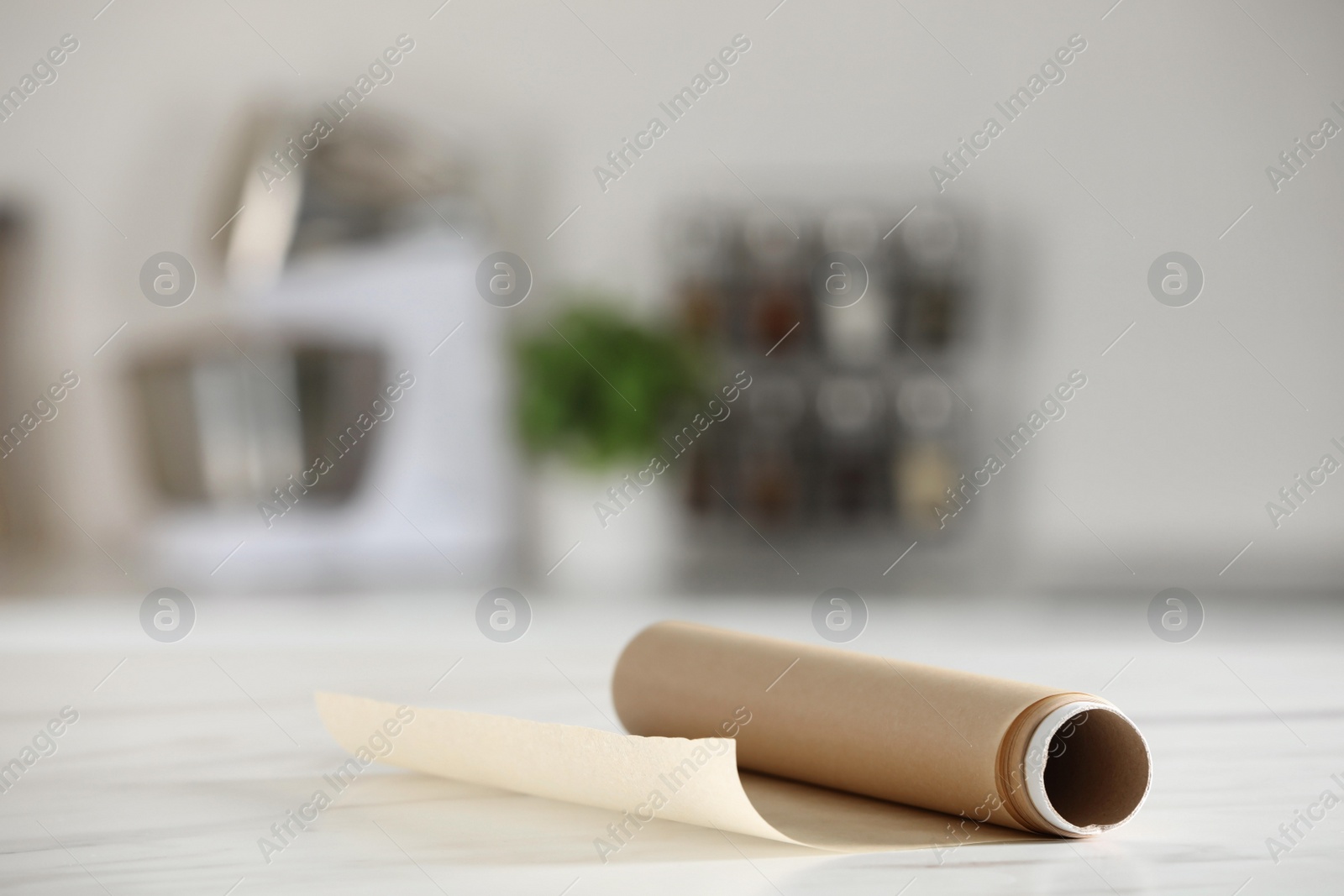 Photo of Roll of baking paper on white marble table against blurred background indoors. Space for text