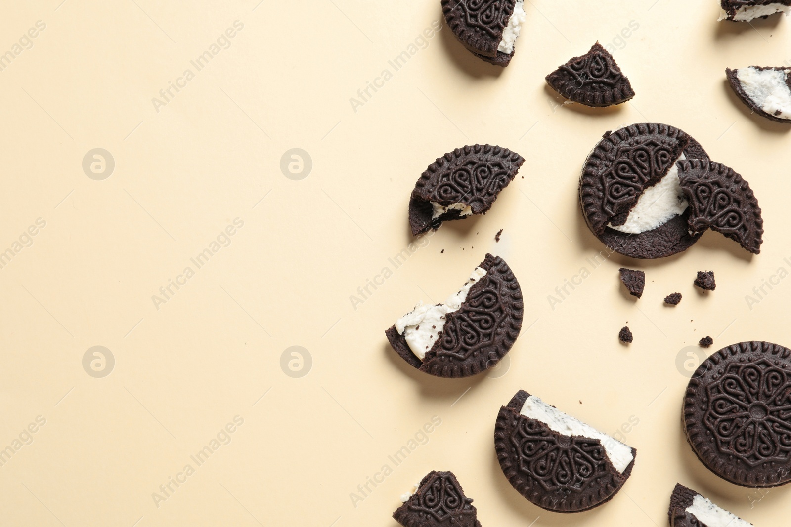 Photo of Tasty chocolate cookies with cream on color background, flat lay. Space for text