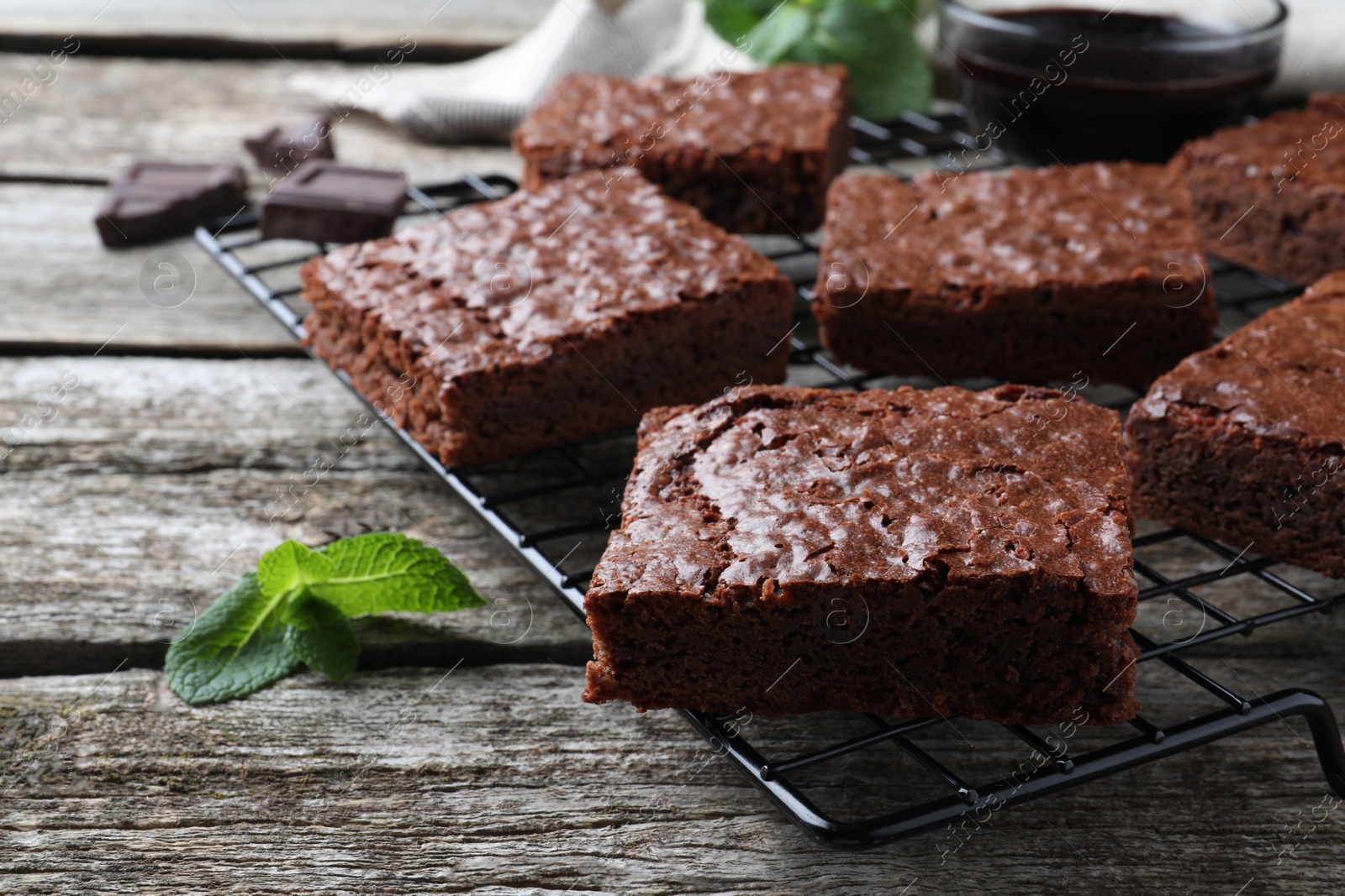 Photo of Cooling rack with delicious chocolate brownies and fresh mint on wooden table, closeup