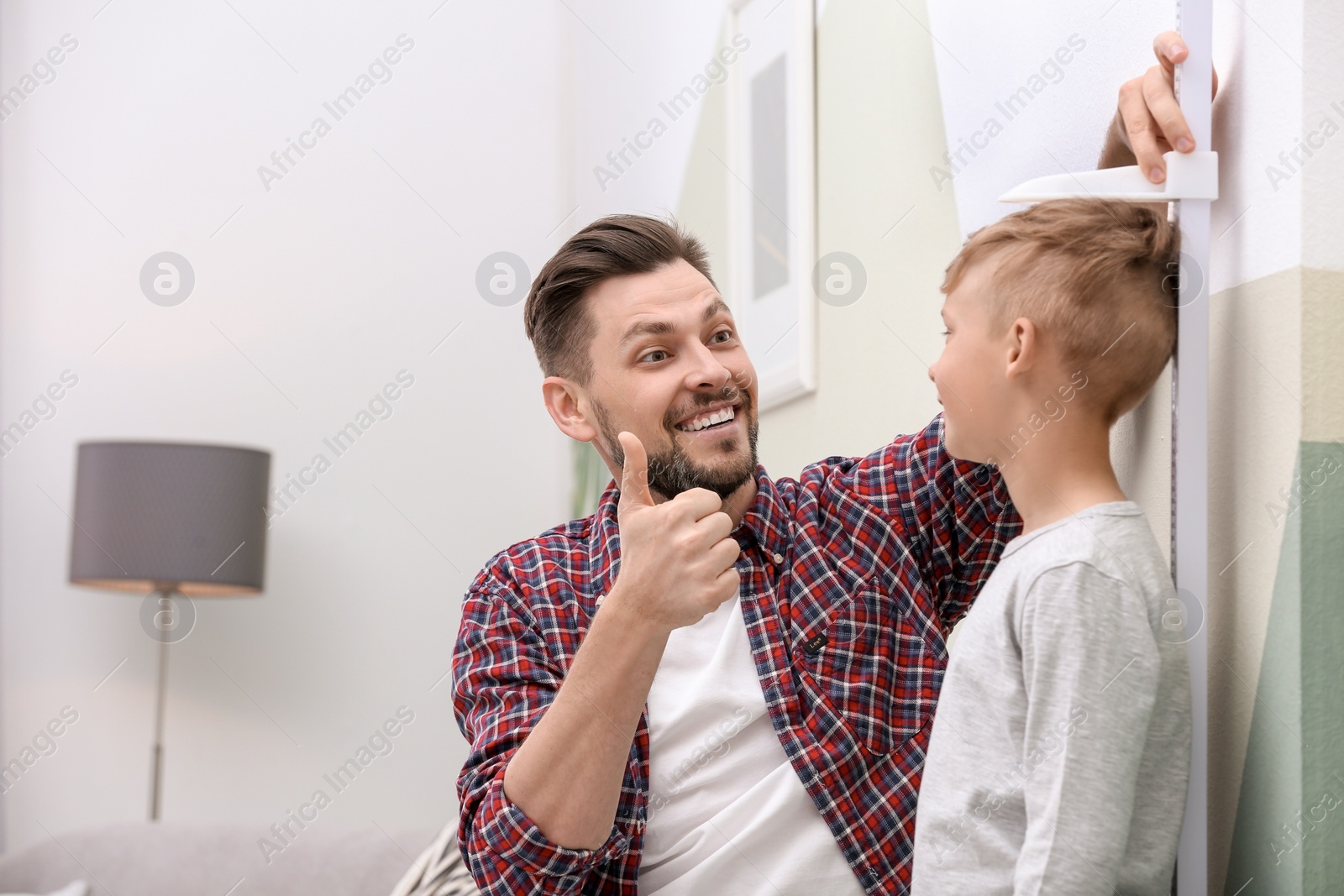 Photo of Young man measuring his son's height at home