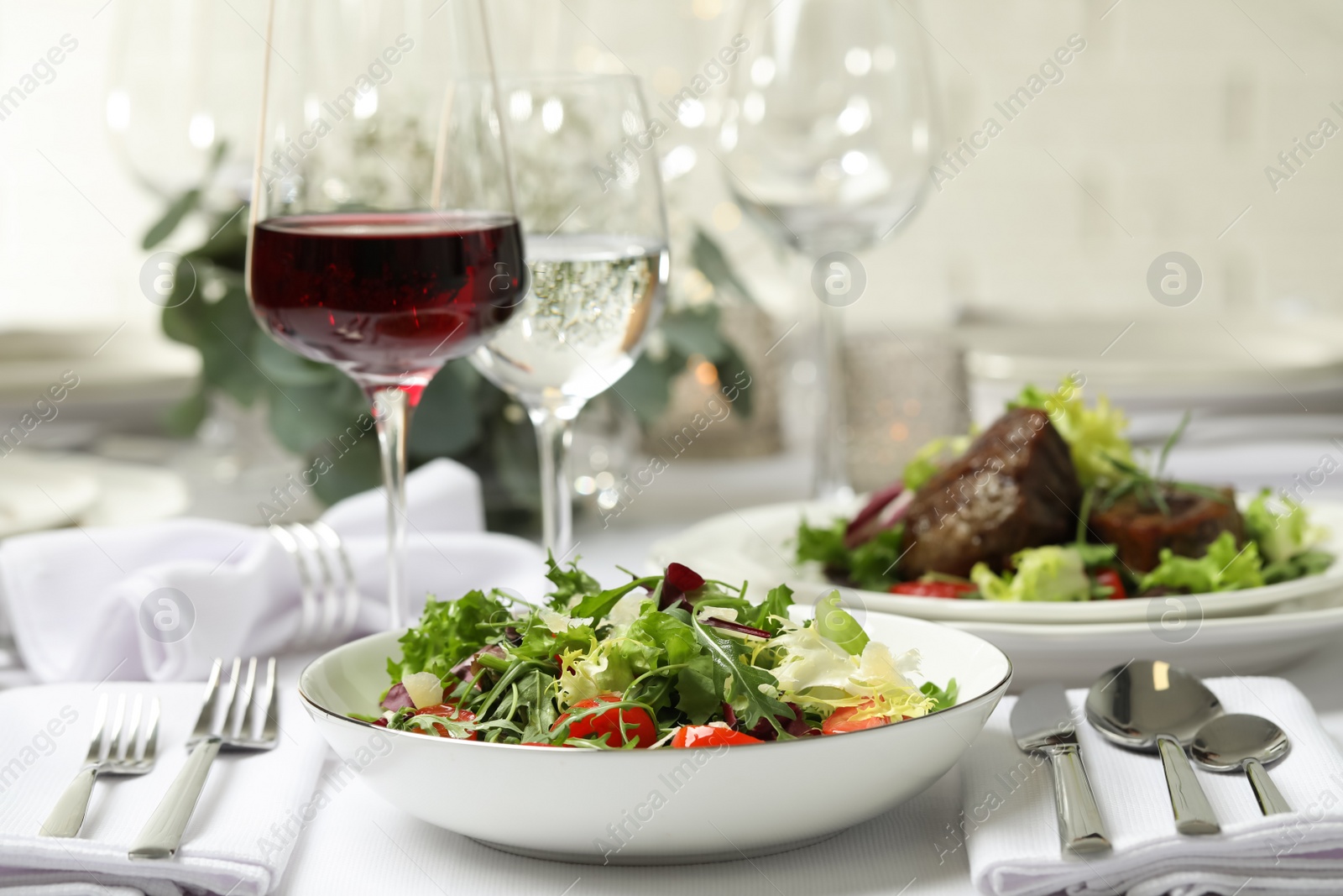 Photo of Delicious salad and wine served on table in restaurant