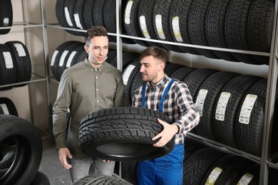 Service center consultant helping customer to choose tire in store