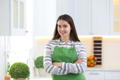 Photo of Portrait of young woman with apron in kitchen