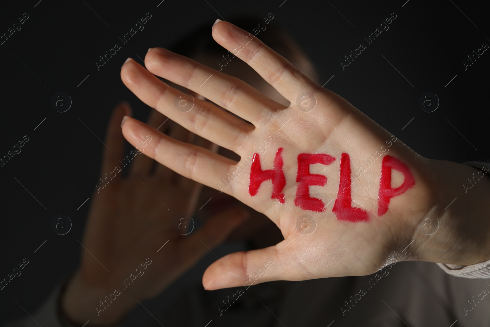 Photo of Woman with word Help written on hand against black background, closeup. Domestic violence concept