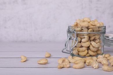 Glass jar with tasty cashew nuts on white wooden table. space for text