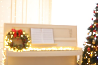 Blurred view of white piano with fairy lights indoors. Christmas music