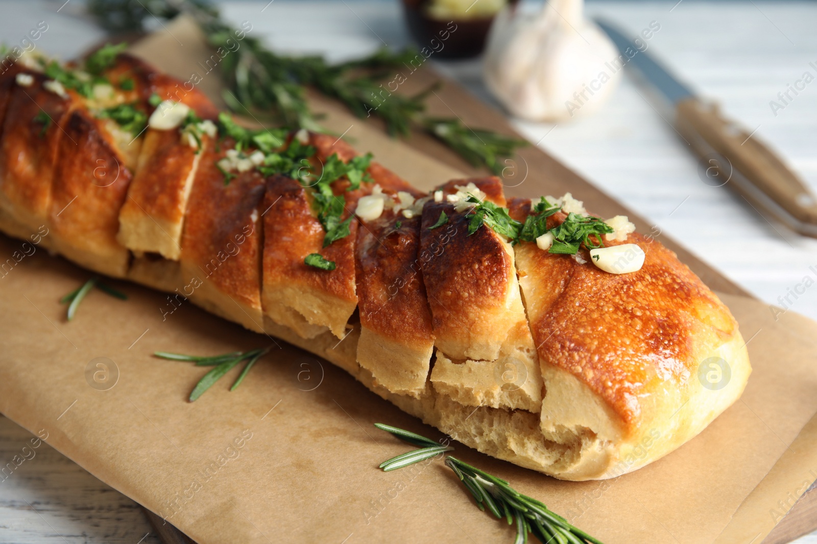 Photo of Delicious homemade garlic bread on parchment paper, closeup