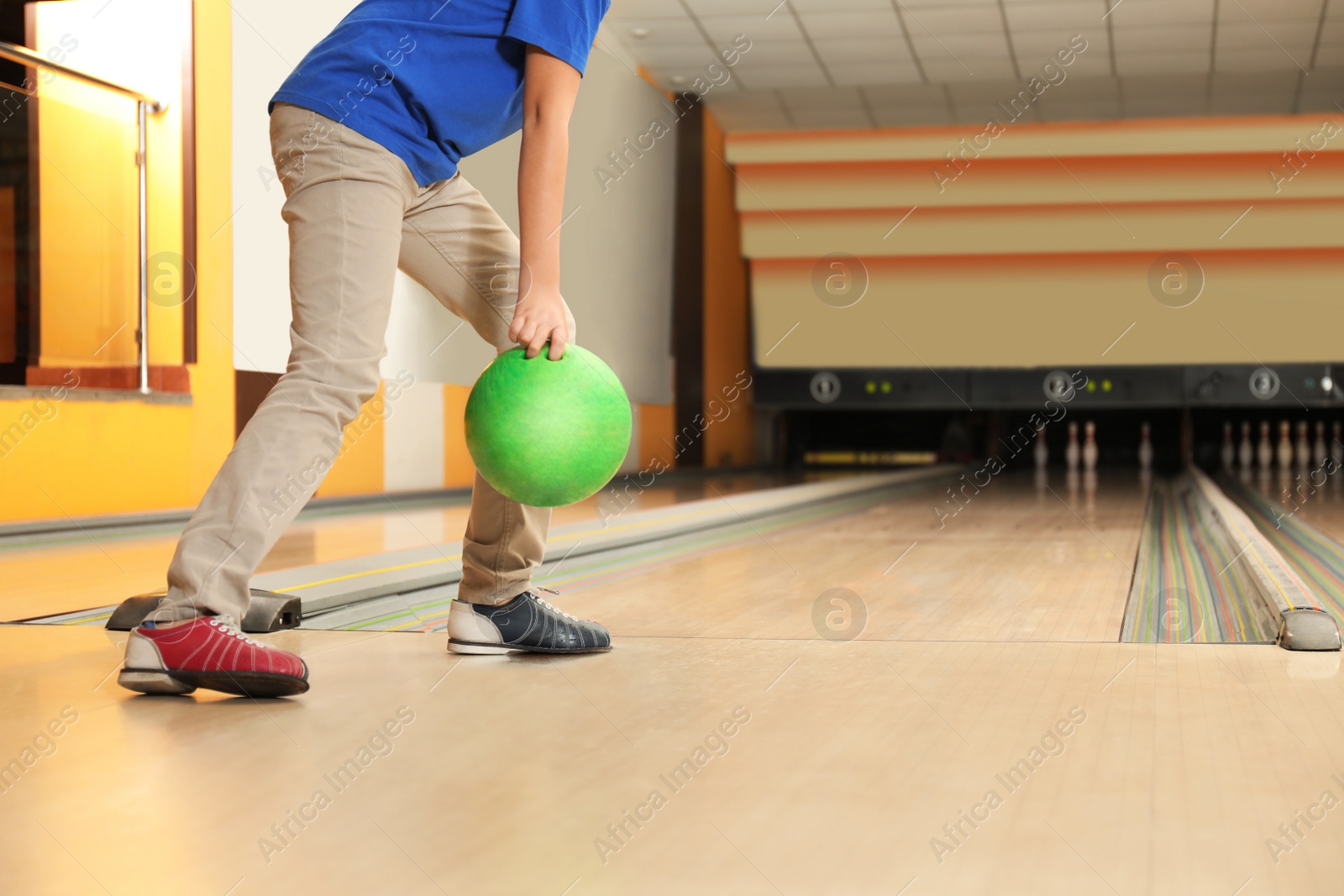 Photo of Little boy throwing ball in bowling club, closeup. Space for text