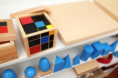 Photo of Set of wooden geometrical objects and other montessori toys on shelves