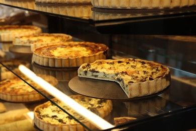 Photo of Different delicious quiches on counter in bakery shop, closeup