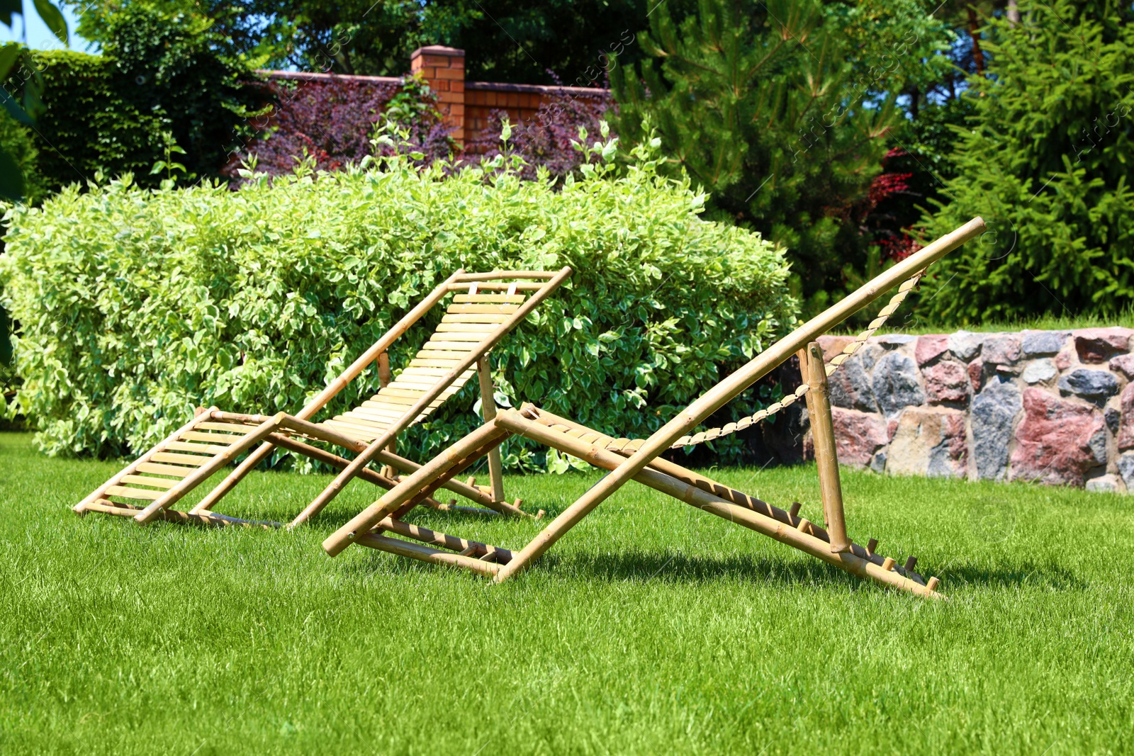 Photo of Wooden deck chairs in beautiful garden on sunny day