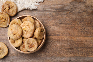 Tasty dried figs in bowl on wooden table, top view. Space for text