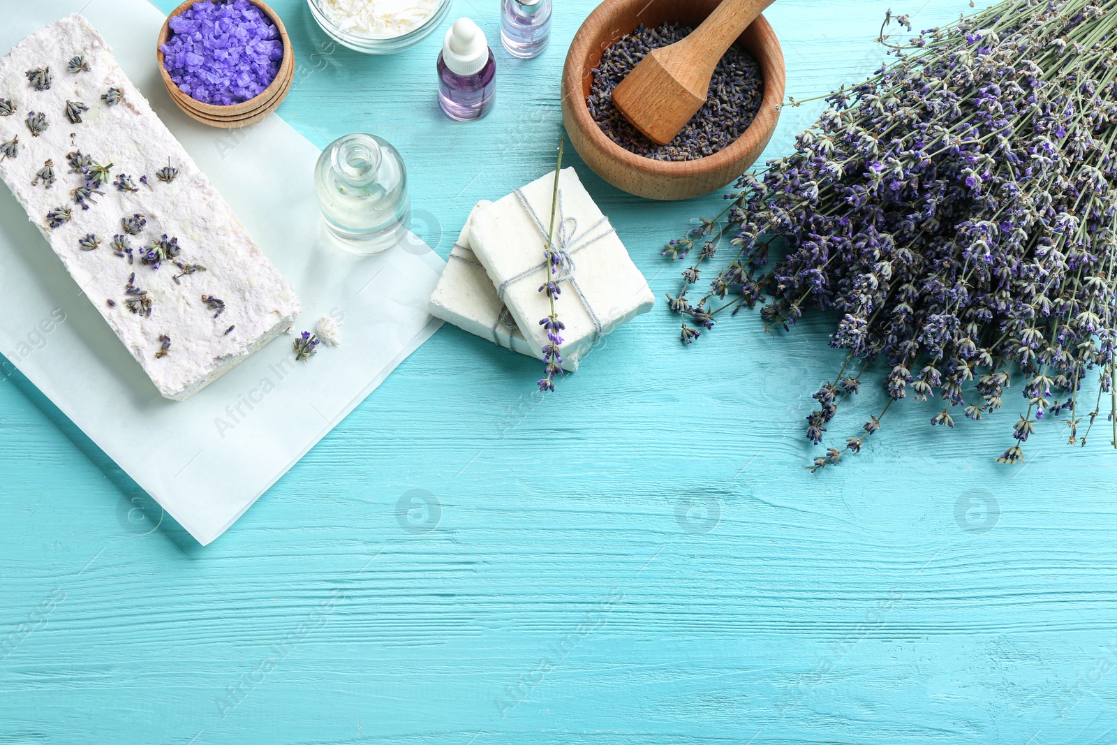 Photo of Flat lay composition with hand made soap bars and lavender flowers on light blue wooden table, space for text