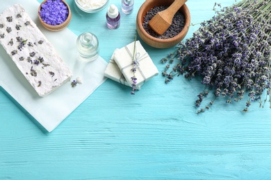 Flat lay composition with hand made soap bars and lavender flowers on light blue wooden table, space for text