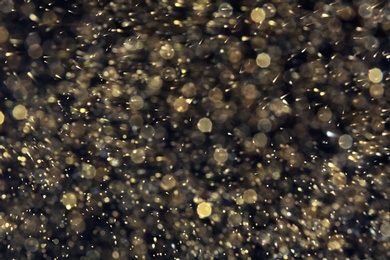 Photo of Golden glitter with bokeh effect on dark background