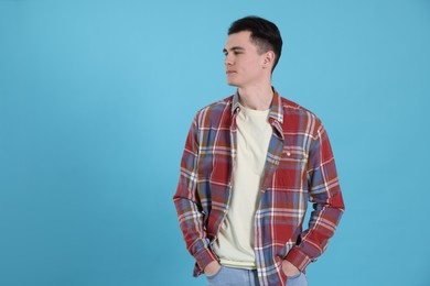 Portrait of handsome young man on light blue background, space for text