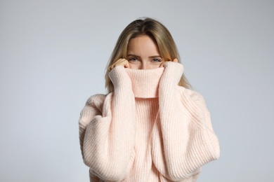 Photo of Beautiful young woman wearing knitted sweater on light grey background