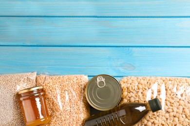 Different products on turquoise wooden table, flat lay. Food donation